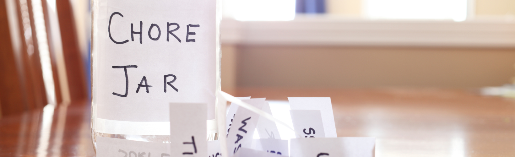 A glass jar labeled “Chore Jar” filled with handwritten slips of household tasks, symbolizing shared household responsibilities and chore organization.