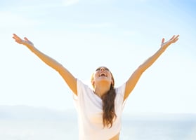 An excited young woman with her hands thrown to the sky, enjoying her free time.